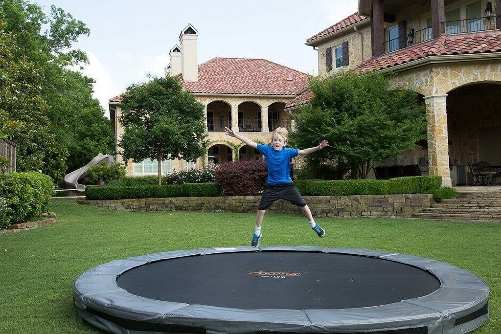 A child jumping on an inground trampoline